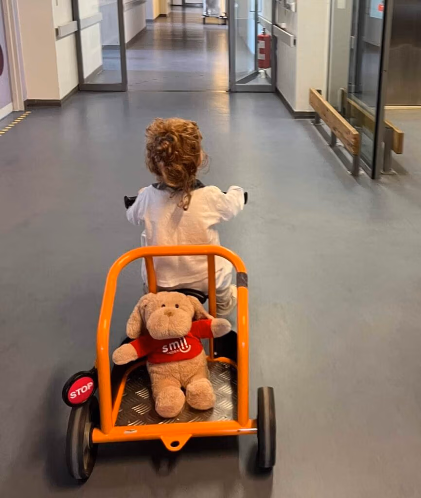 Barn cykler gennem gang med bamse i orange anhænger